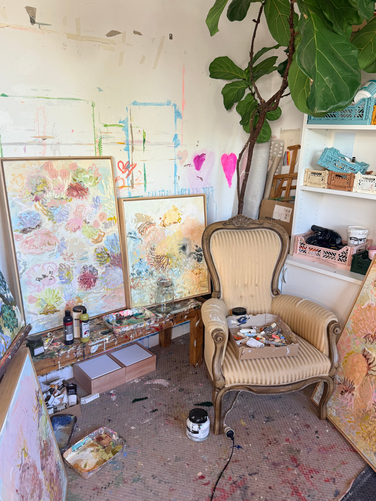 Beneath the Surface displayed with other FLOAT paintings beside an upholstered chair in Prudence De Marchi's studio.