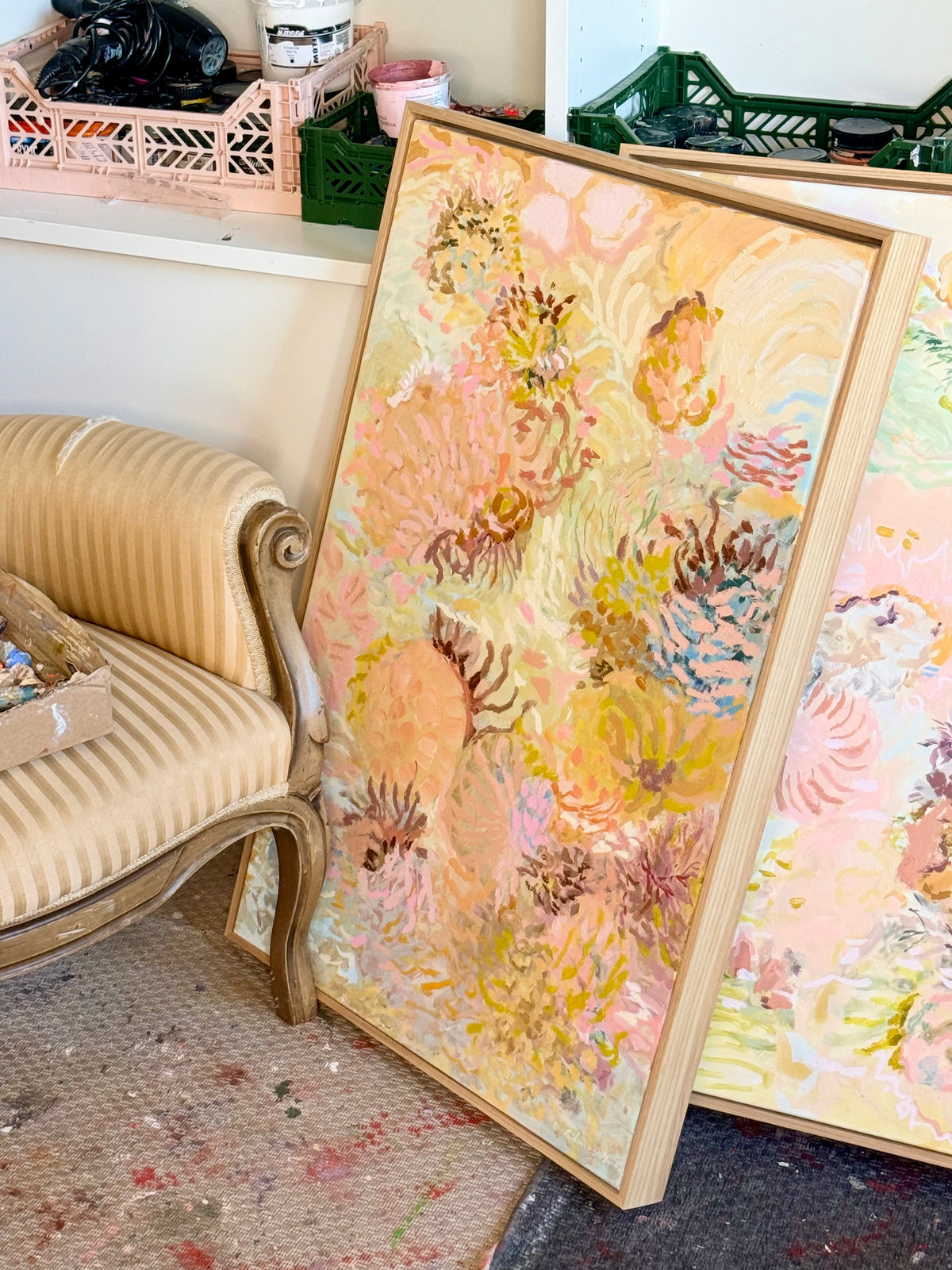 Original Coral Wandering painting by Prudence De Marchi leaning beside an upholstered chair in her studio.