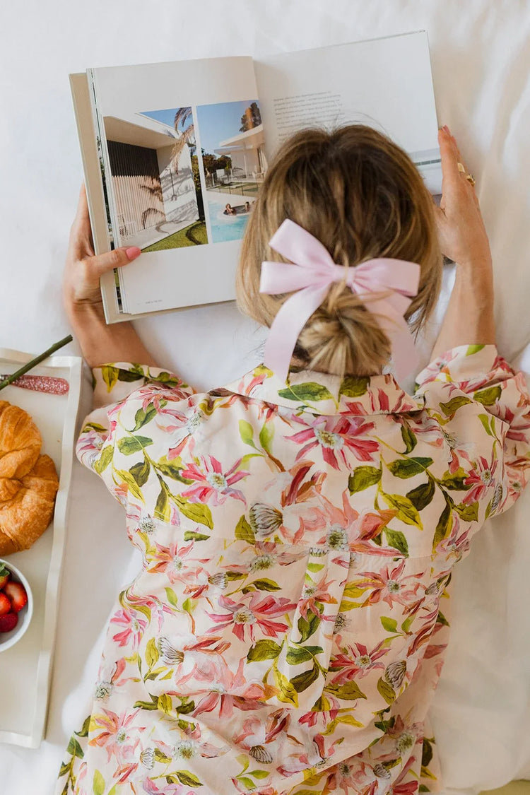 Woman laying in bed with floral pyjama reading a magazine.