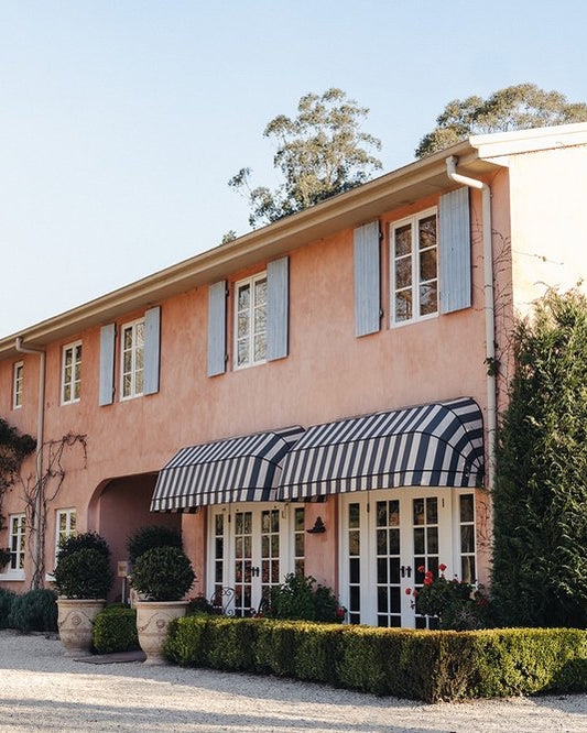 Pink building with striped awning and garden in front