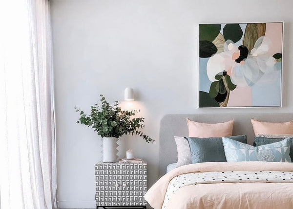 Neatly arranged bedroom with a bed, nightstand, and decorative wall art.