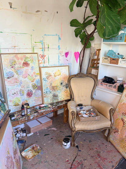 Beneath the Surface displayed with other FLOAT paintings beside an upholstered chair in Prudence De Marchi's studio.