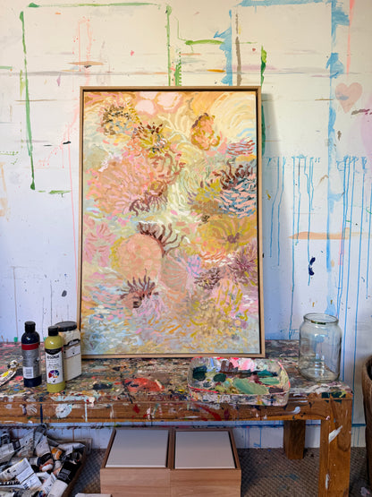 Coral Wanderings original painting in a timber frame on a paint-covered studio table.
