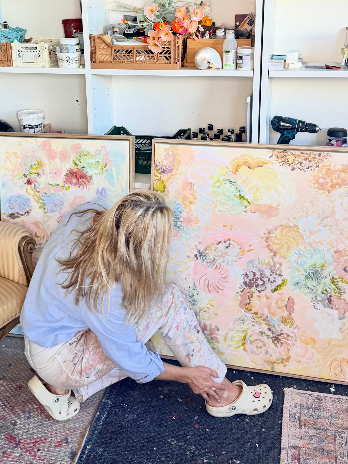 Prudence De Marchi crouching beside Under the Waves while arranging FLOAT paintings in her studio.